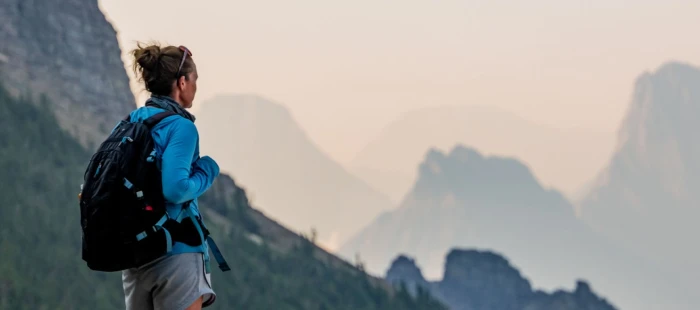 A hiker with a backpack looking at mountains in the distance.